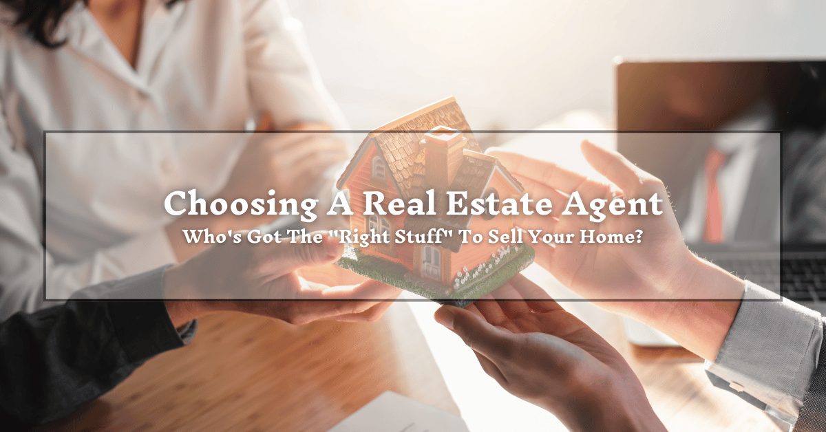 A group of hands holding a small model house over a wooden table. The text overlay reads, "Choosing A Real Estate Agent: Who's Got The 'Right Stuff' To Sell Your Home?" The background shows a person in a white shirt and a laptop on the side.