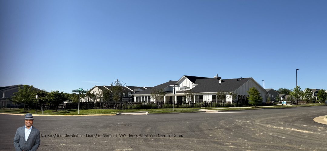 A wide view of the Cascades at Embry Mills residential community center complex with modern white and gray buildings, surrounded by green lawns and trees, under a clear blue sky. In the foreground, a man in a suit and hat is standing on the edge of a paved road. Text at the bottom reads: "Looking for Elevated 55+ Living in Stafford, VA? Here's What You Need to Know."