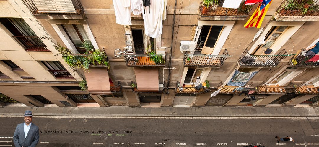 A view from above shows an apartment building with several small balconies adorned with plants and laundry. A street runs below with a person walking a dog. An inset image of a man in a hat and suit is in the lower left corner. Text overlay reads: "3 Clear Signs It’s Time to Say Goodbye to Your Home."