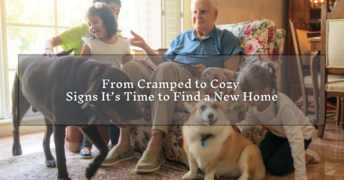An elderly man sitting on a floral-patterned sofa, surrounded by family and pets in a cozy living room. A young girl and a boy are playing nearby with a large dog and a corgi. The text overlay reads, "From Cramped to Cozy: Signs It's Time to Find a New Home."